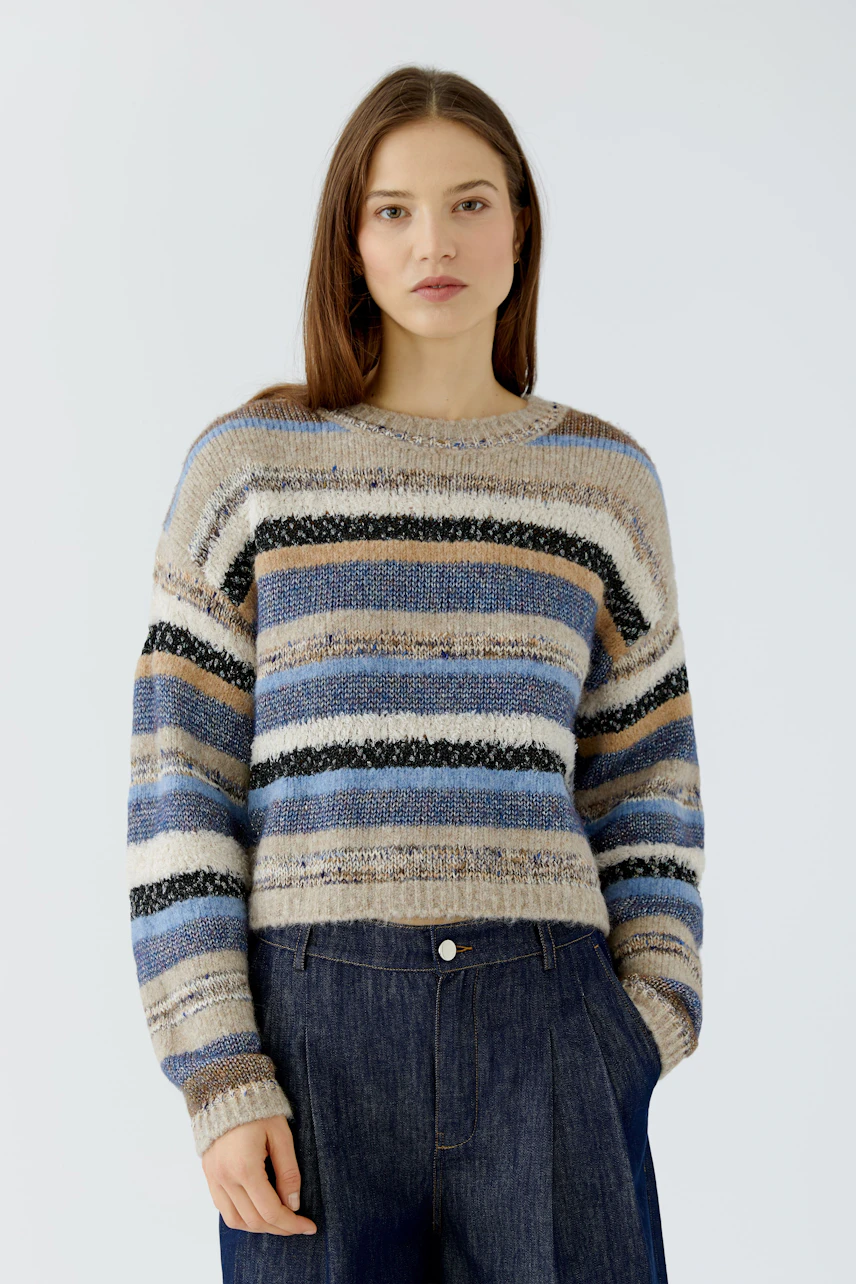 Casual women's pullover: Woman in striped pullover with earthy tones and relaxed fit, paired with dark jeans.