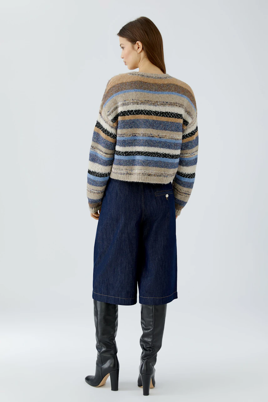 Striped pullover: Woman in a cozy, multicolored striped pullover, paired with denim culottes and tall boots.