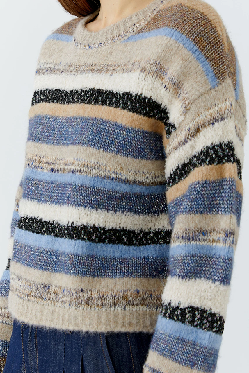 Casual women's pullover: Woman in a cozy striped pullover with earthy tones and blue accents.