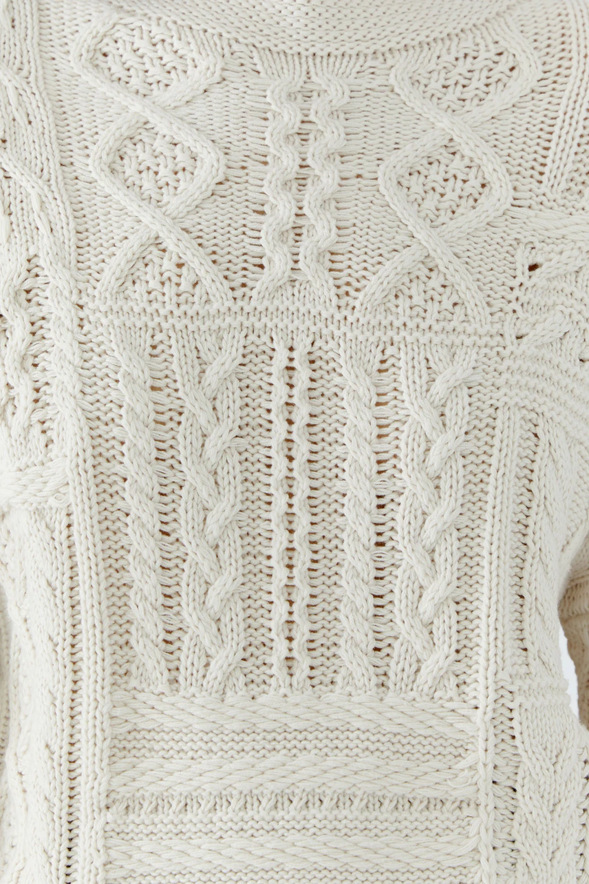 Textured knit pullover in cream with intricate patterns, showcasing a cozy and stylish design.