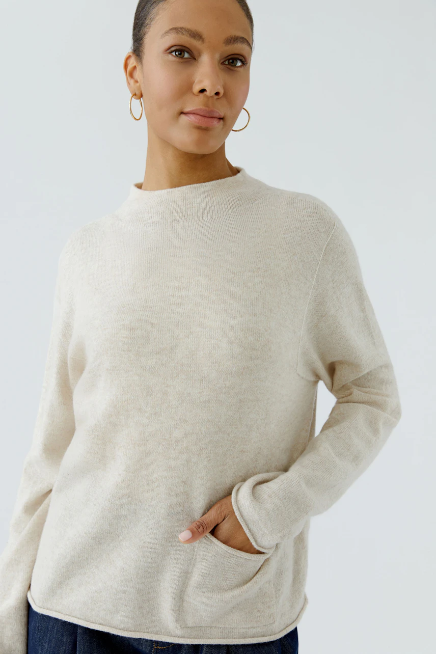 Casual women's pullover: Woman in a soft beige pullover with long sleeves and a relaxed fit.