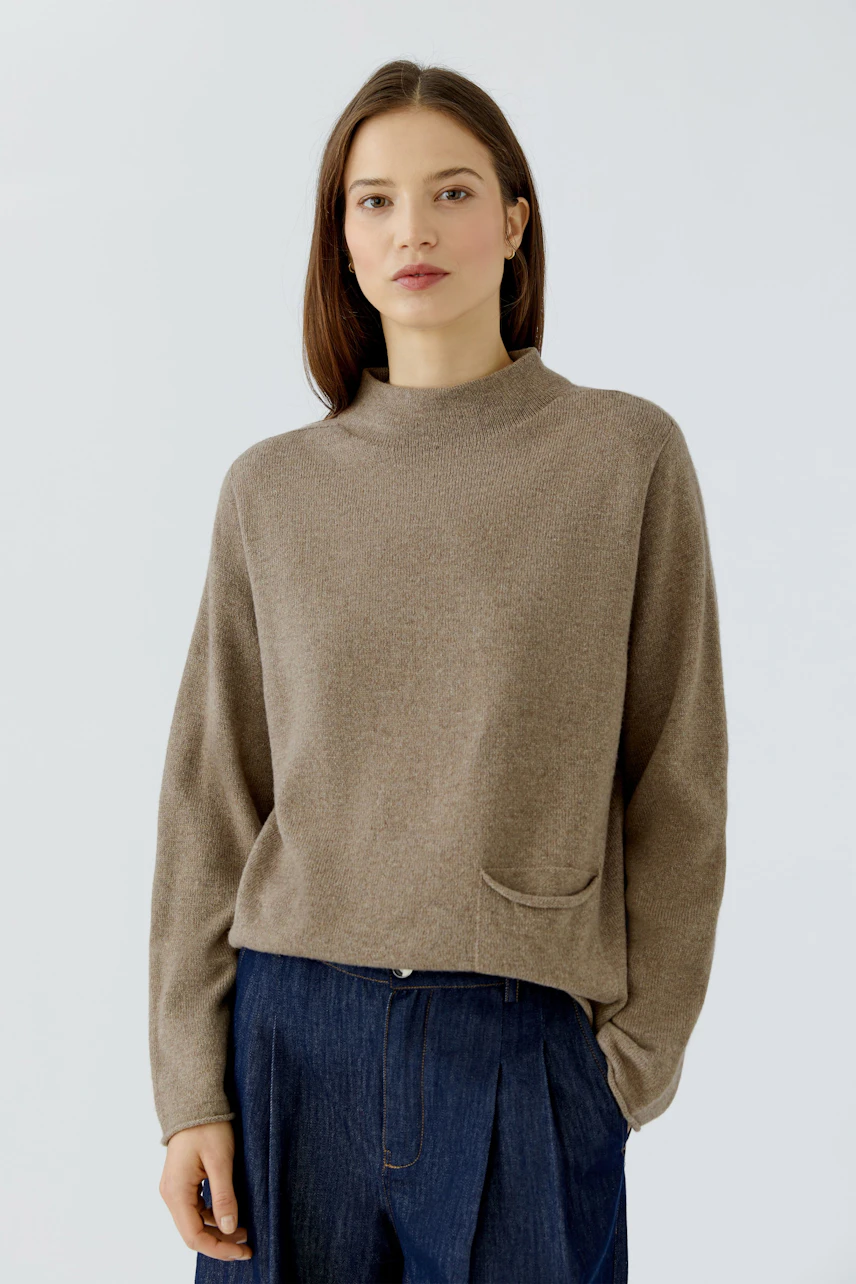 Casual women's pullover: Woman in a brown pullover with relaxed fit and blue jeans, looking composed.