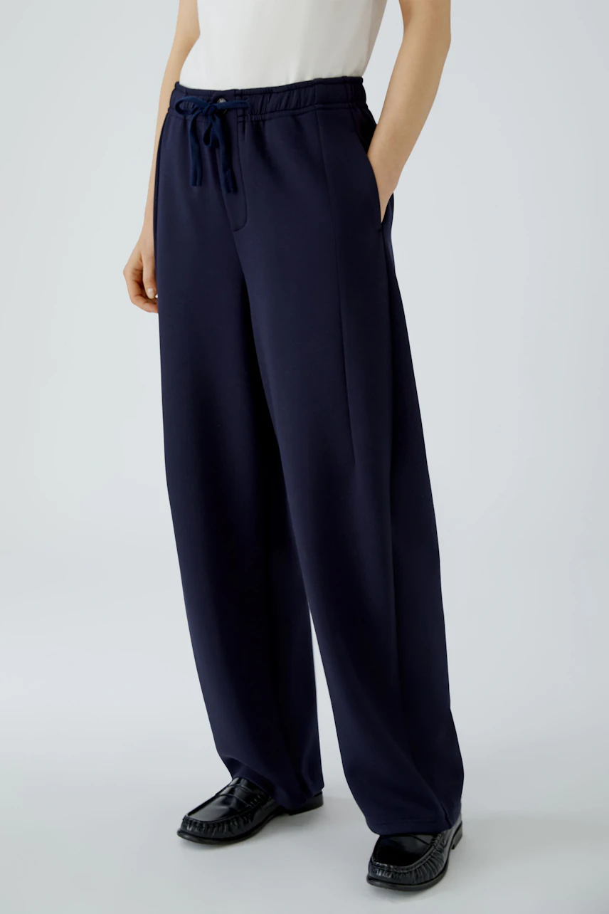 Casual women's pants: Woman in navy blue wide-leg pants with drawstring waist, hands in pockets.
