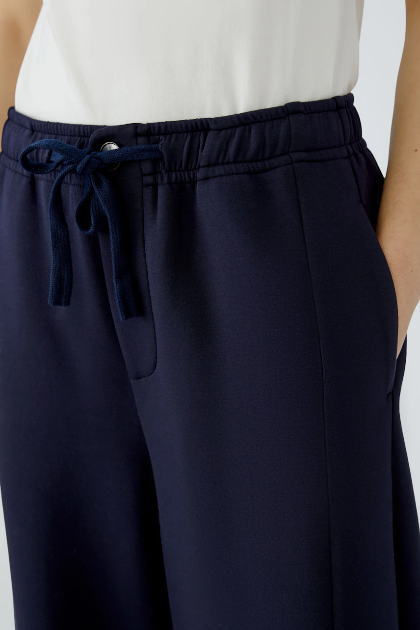 Casual women's pants: Navy drawstring pants with a relaxed fit, worn by a woman in a white top.