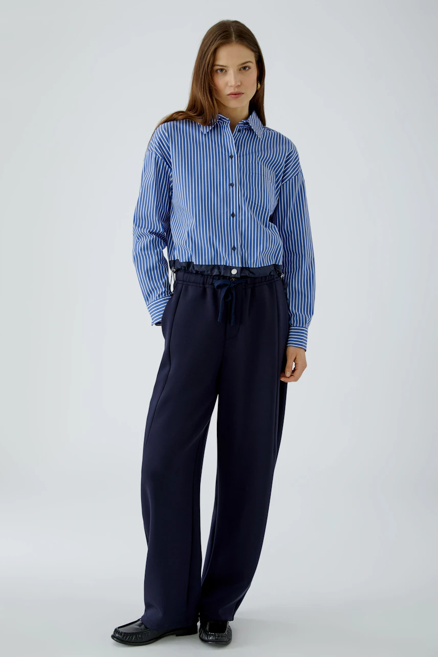 Casual women's pants: Woman in navy wide-leg pants with a blue striped shirt, standing confidently.
