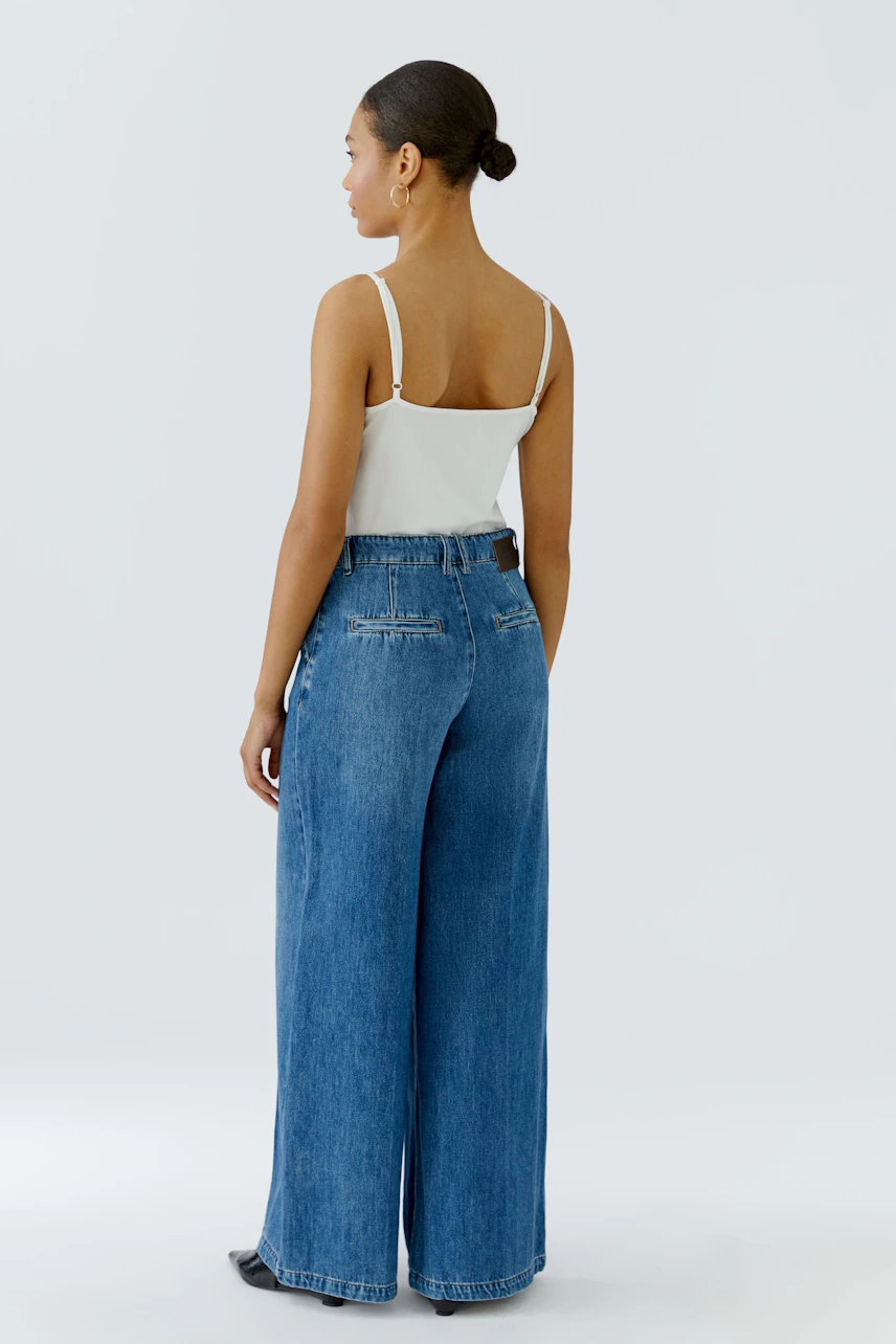 Woman in wide leg jeans and white top, showcasing relaxed fit and modern style.