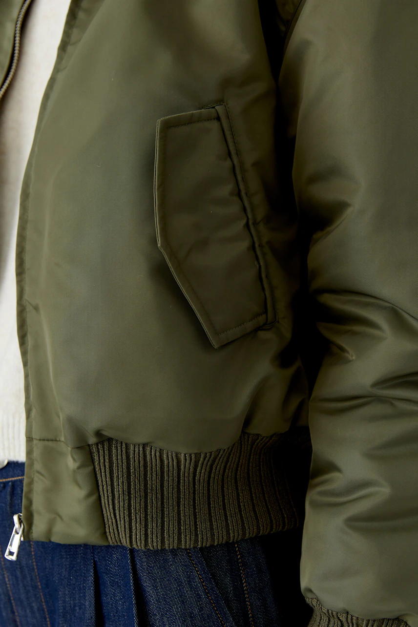 Casual blouson jacket: Woman in olive green blouson with ribbed cuffs and denim skirt.