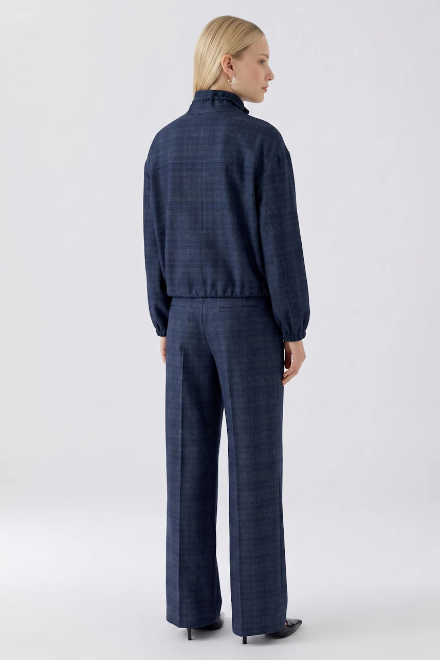 Casual women's jacket: Woman in a blue checkered jacket and matching pants, viewed from the back.