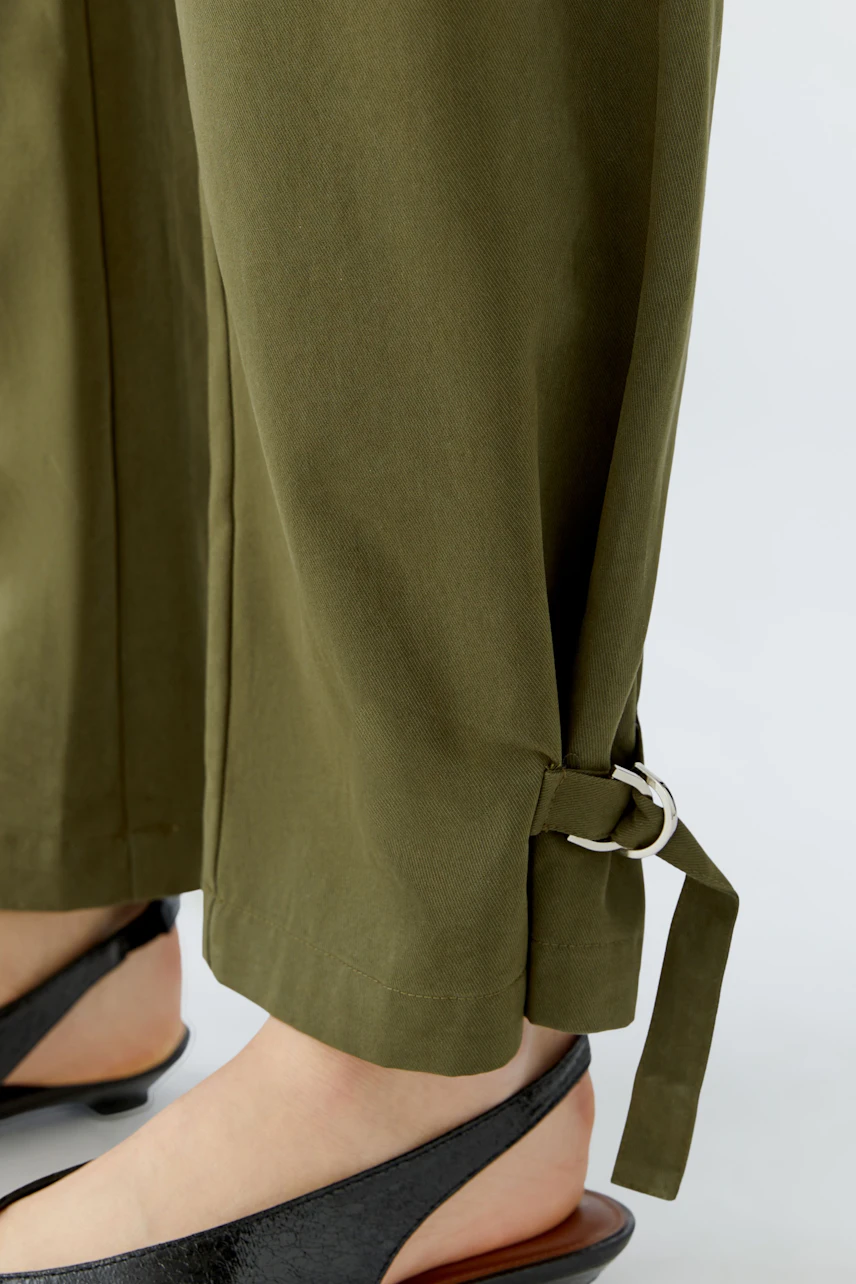 Casual women's pants: Olive green pants with adjustable ankle ties, paired with black sandals.