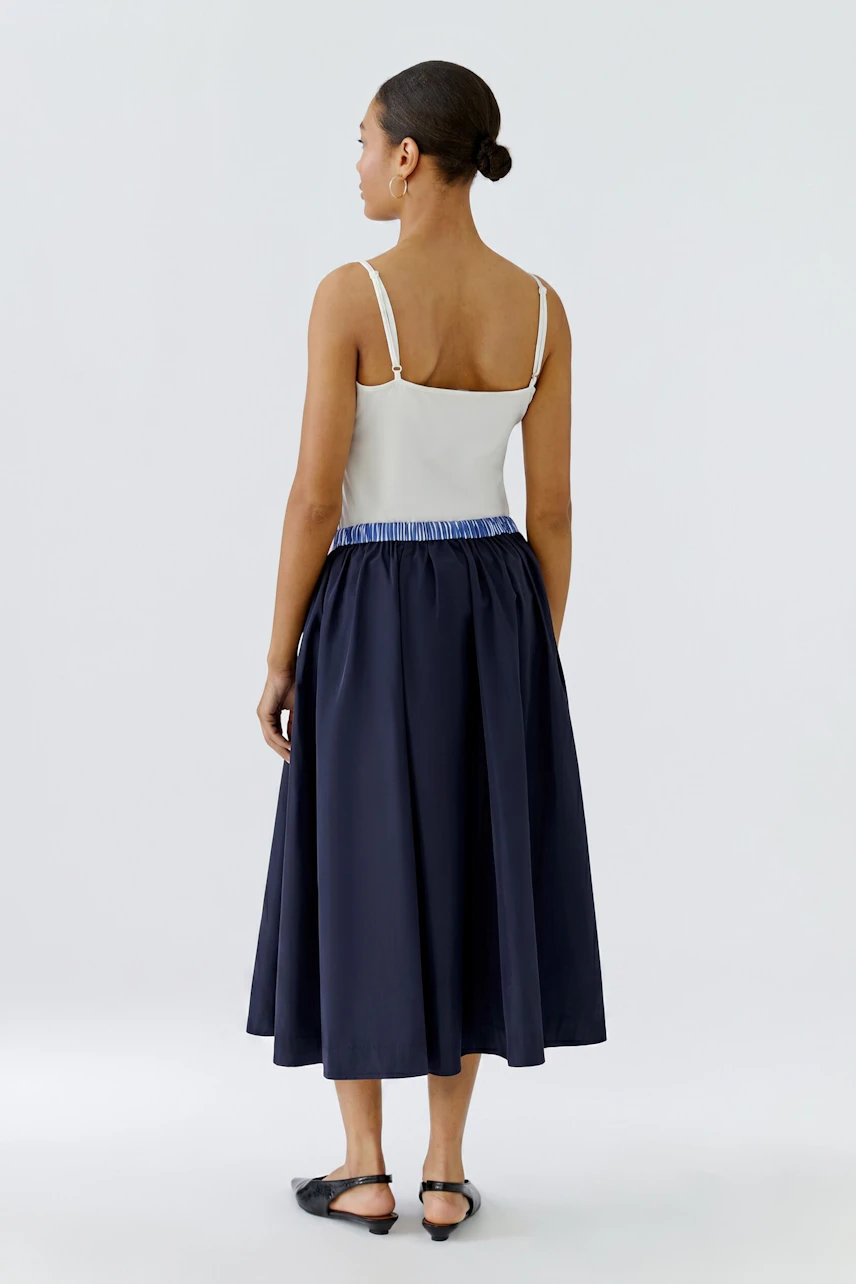 Woman in a navy midiskirt with a white top, showcasing a casual and stylish look.