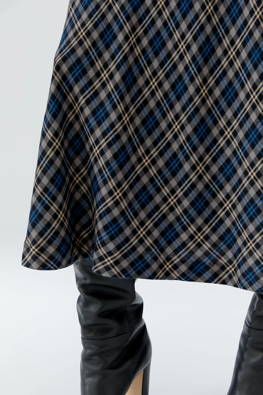 A-line skirt: Woman in plaid A-line skirt with black knee-high boots.
