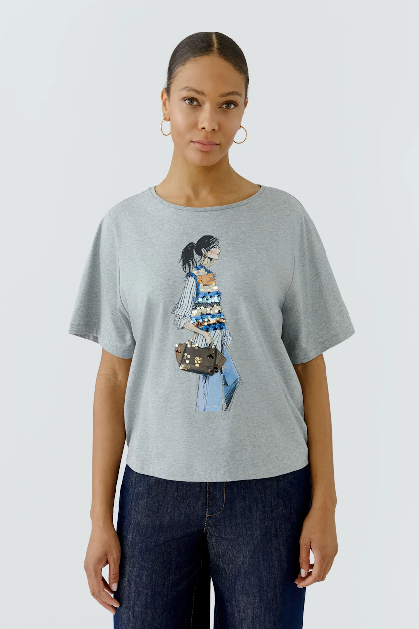 Casual women's T-shirt: Woman in a gray T-shirt with a stylish print, paired with dark jeans.