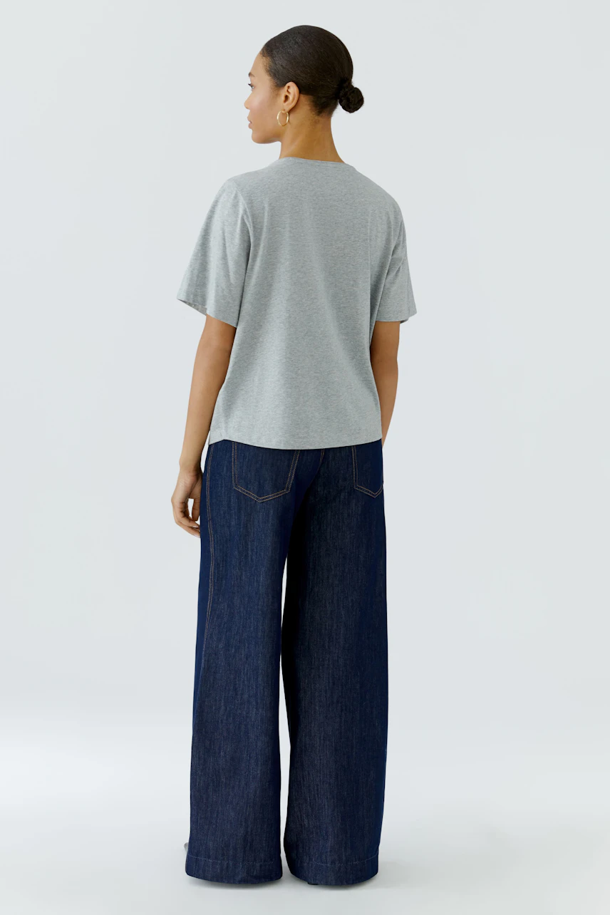 Casual T-shirt: Woman in a grey T-shirt and wide-leg jeans, viewed from the back.