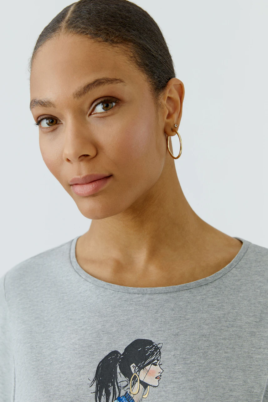 Casual women's T-shirt: Woman in a gray T-shirt with a graphic print, looking confidently.