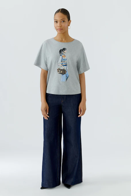Graues Damen-T-Shirt mit Print: Frau in lässigem Outfit mit Tasche, ideal für einen entspannten Look.