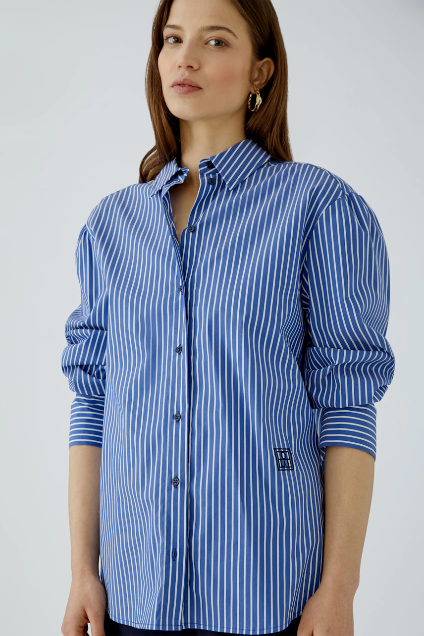 Casual women's shirt blouse: Woman in blue striped blouse with button-up front and relaxed fit.