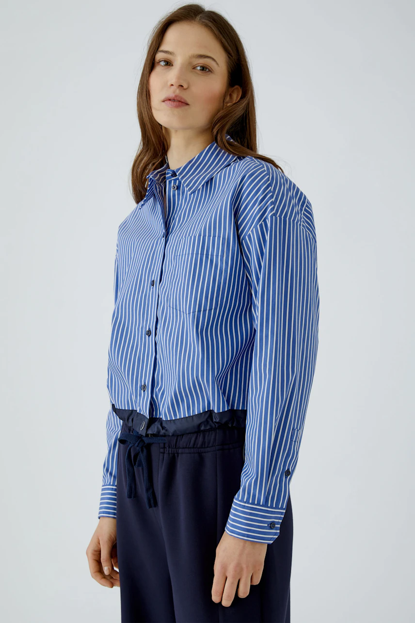 Striped shirt blouse: Woman in blue and white striped blouse with navy pants, looking confidently.