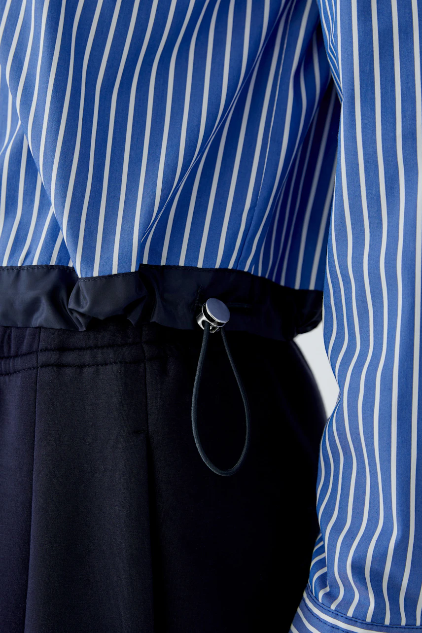 Striped shirt blouse: Close-up of blue and white striped blouse with adjustable waist detail.