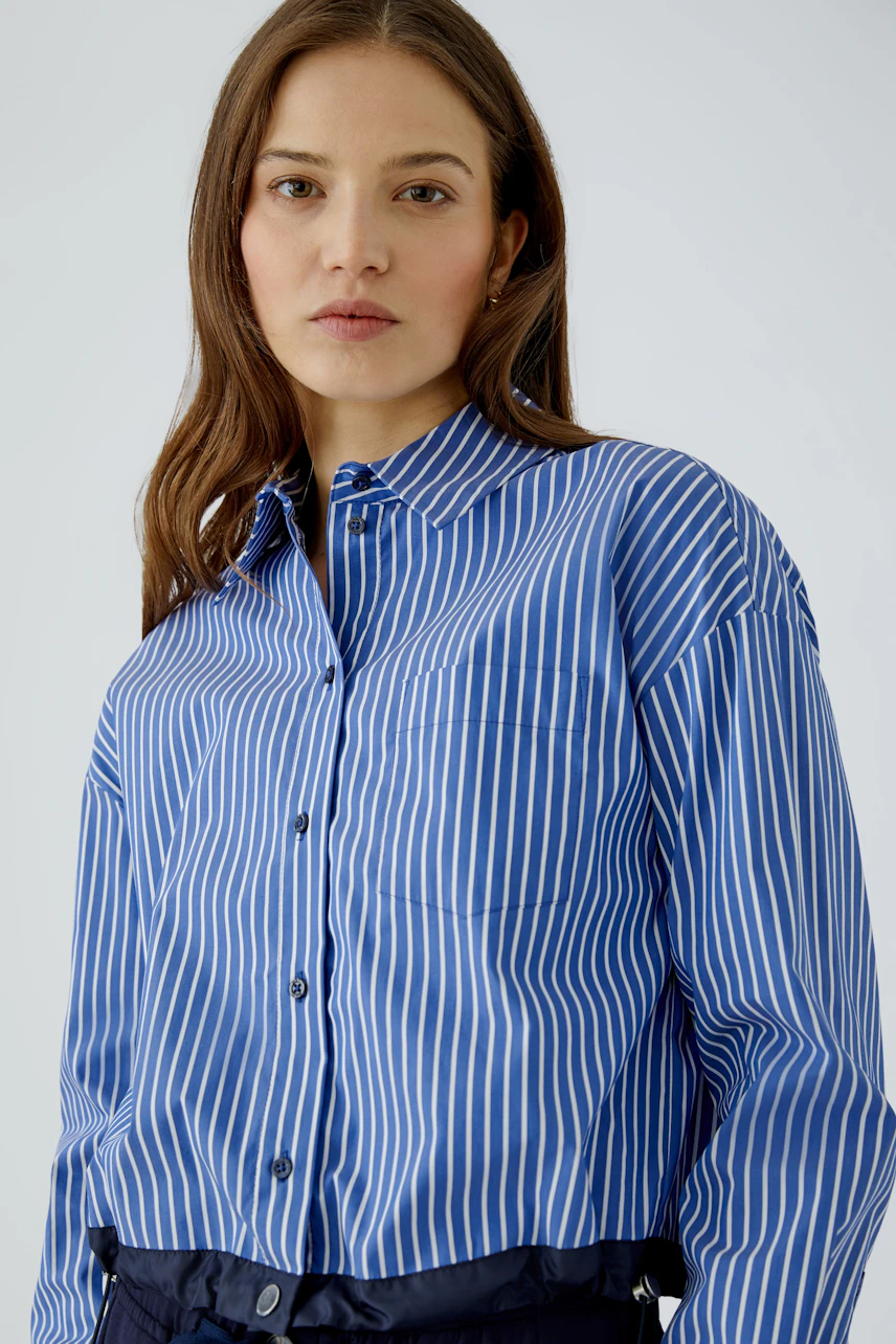 Striped shirt blouse: Woman in blue and white striped blouse, relaxed fit, looking confidently.