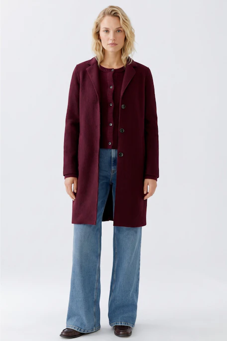 Wool coat: A woman in a burgundy wool coat with a classic collar and button closure.