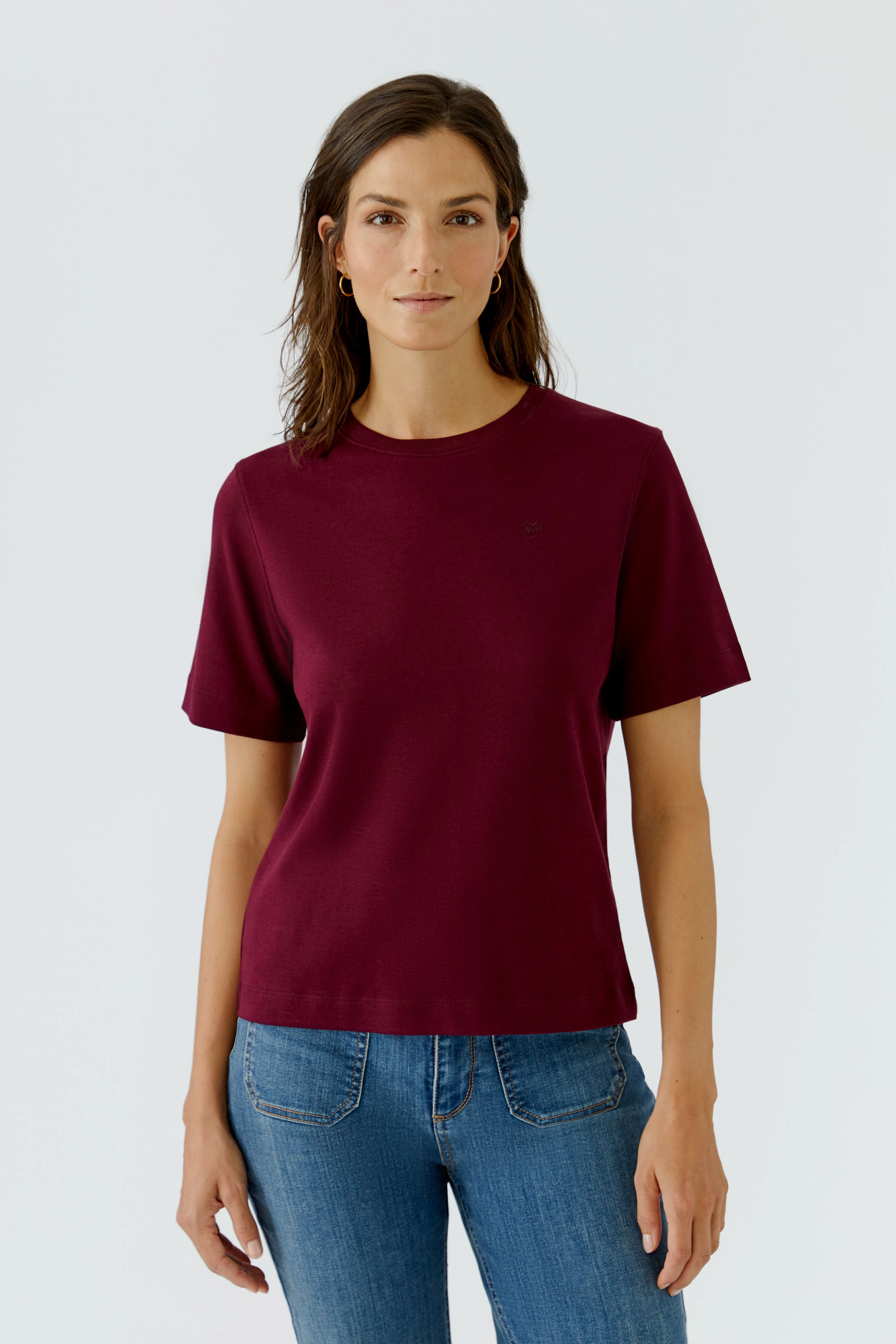 Lässiges Damen-T-Shirt: Frau im weinroten T-Shirt und blauen Jeans, schlicht und modern.