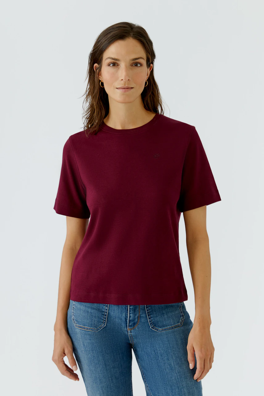 Lässiges Damen-T-Shirt: Frau im weinroten T-Shirt und blauen Jeans, schlicht und modern.