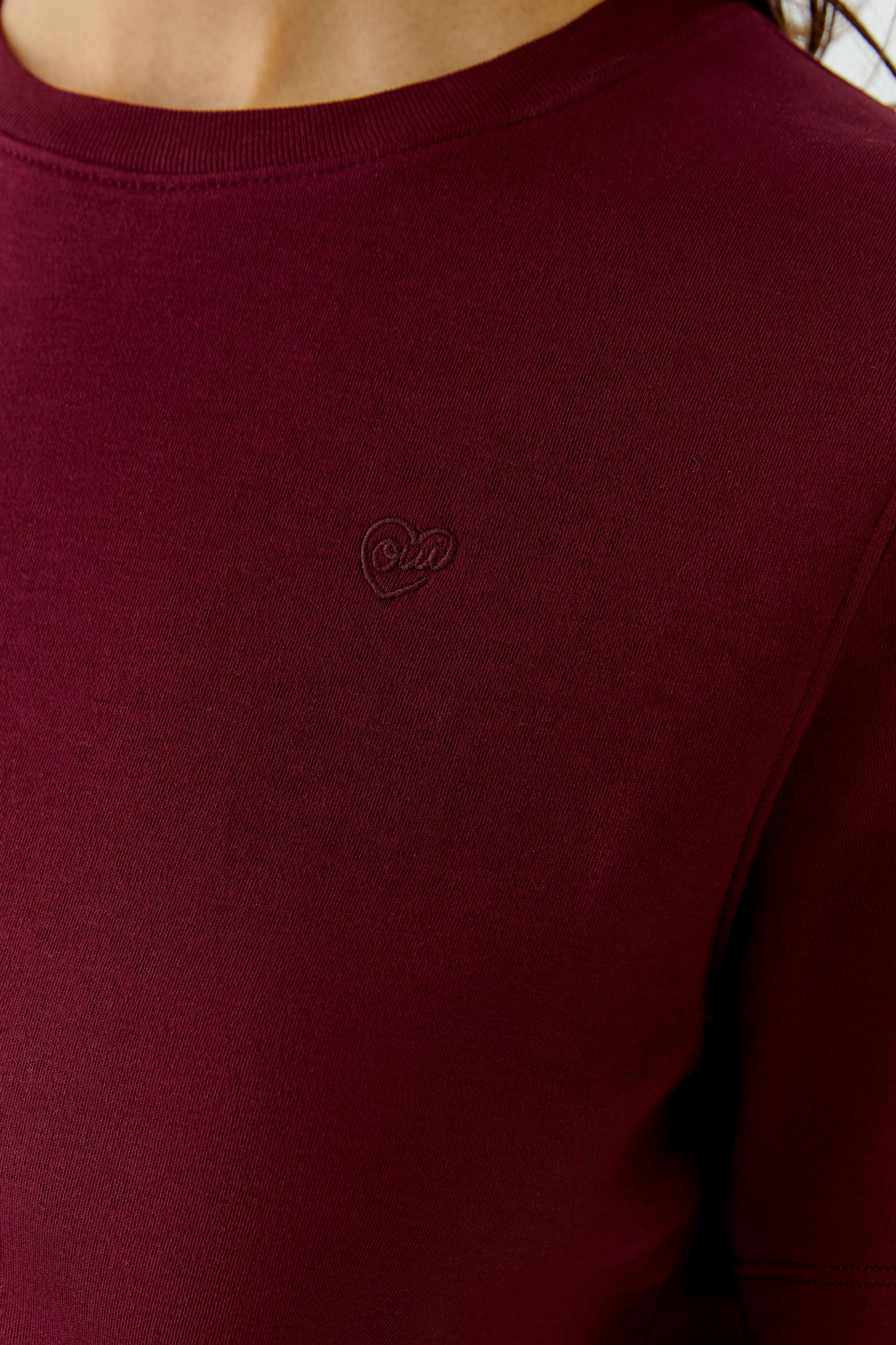 Bordeauxrotes Damen-T-Shirt: Frau trägt schlichtes T-Shirt mit kleinem Herz-Logo auf der Brust.