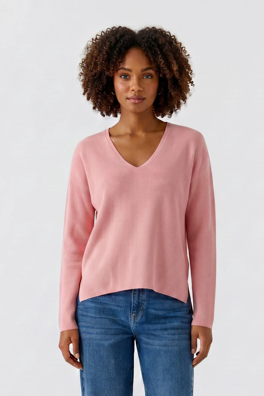 Casual women's pullover: Woman in a pink V-neck pullover and blue jeans, standing confidently.