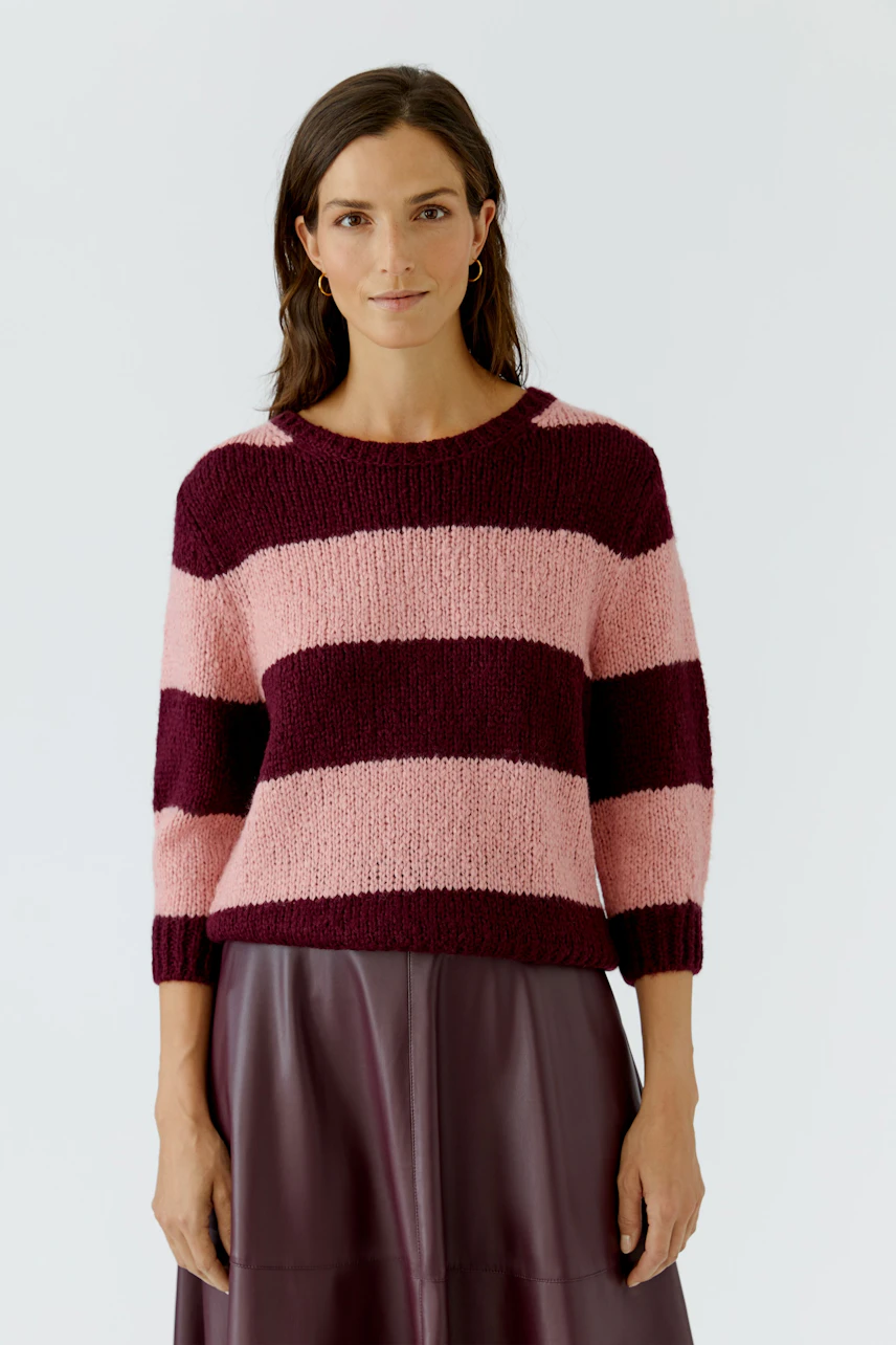 Frau im gestreiften Pullover in Rosa und Bordeaux, kombiniert mit einem Rock. Lässig und modern.