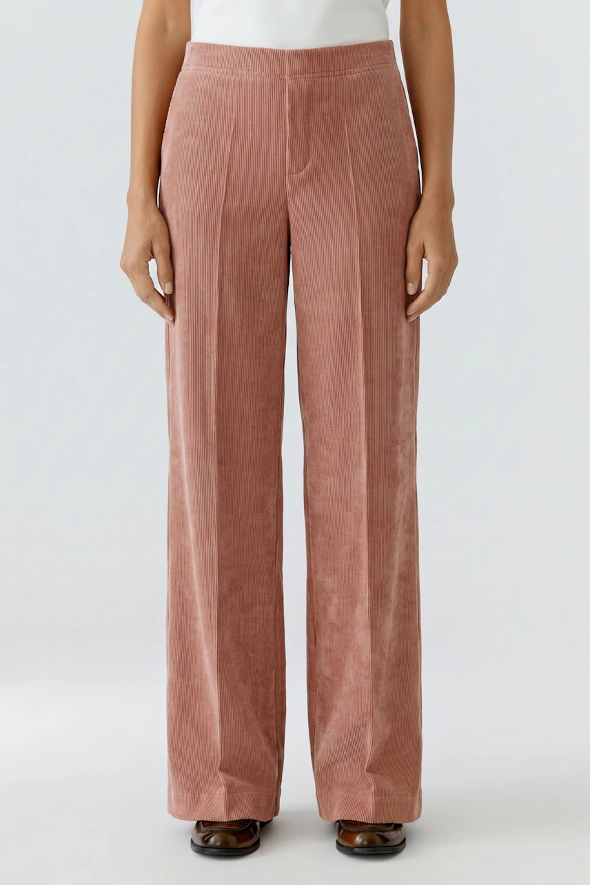 Frau in rosafarbener Cordhose, gerade geschnitten, mit weißem Oberteil. Lässiger Look für jeden Tag.
