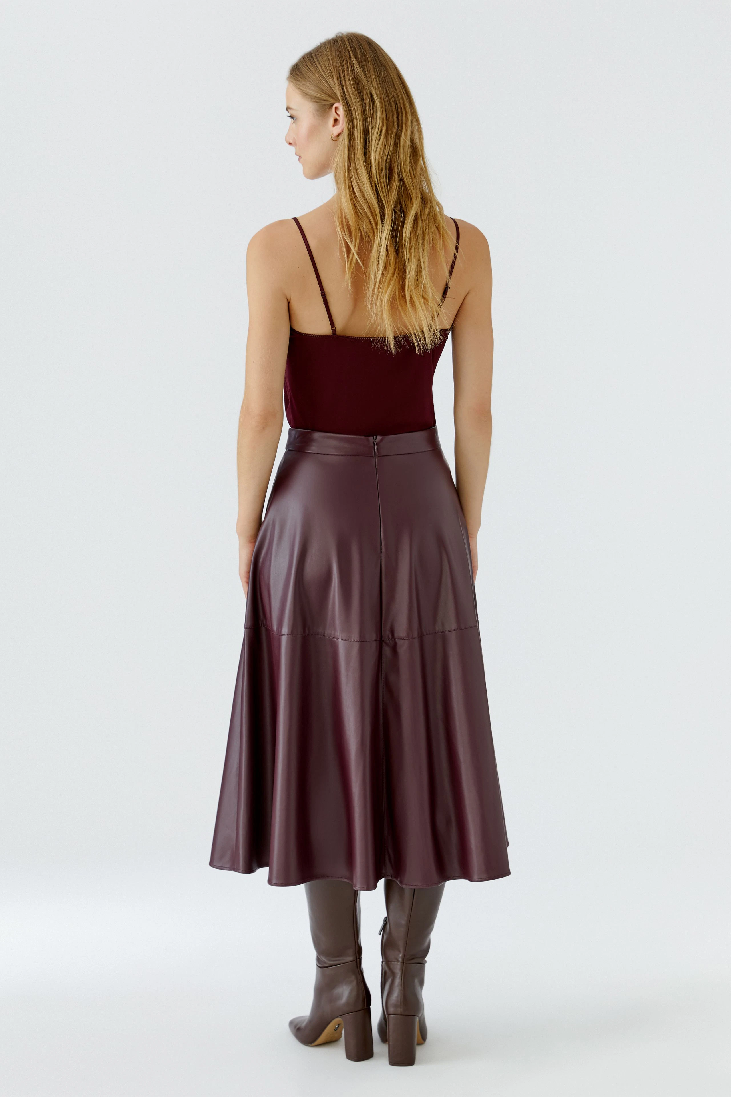 A-line skirt: Woman in a burgundy A-line skirt with a matching top and knee-high boots, viewed from behind.