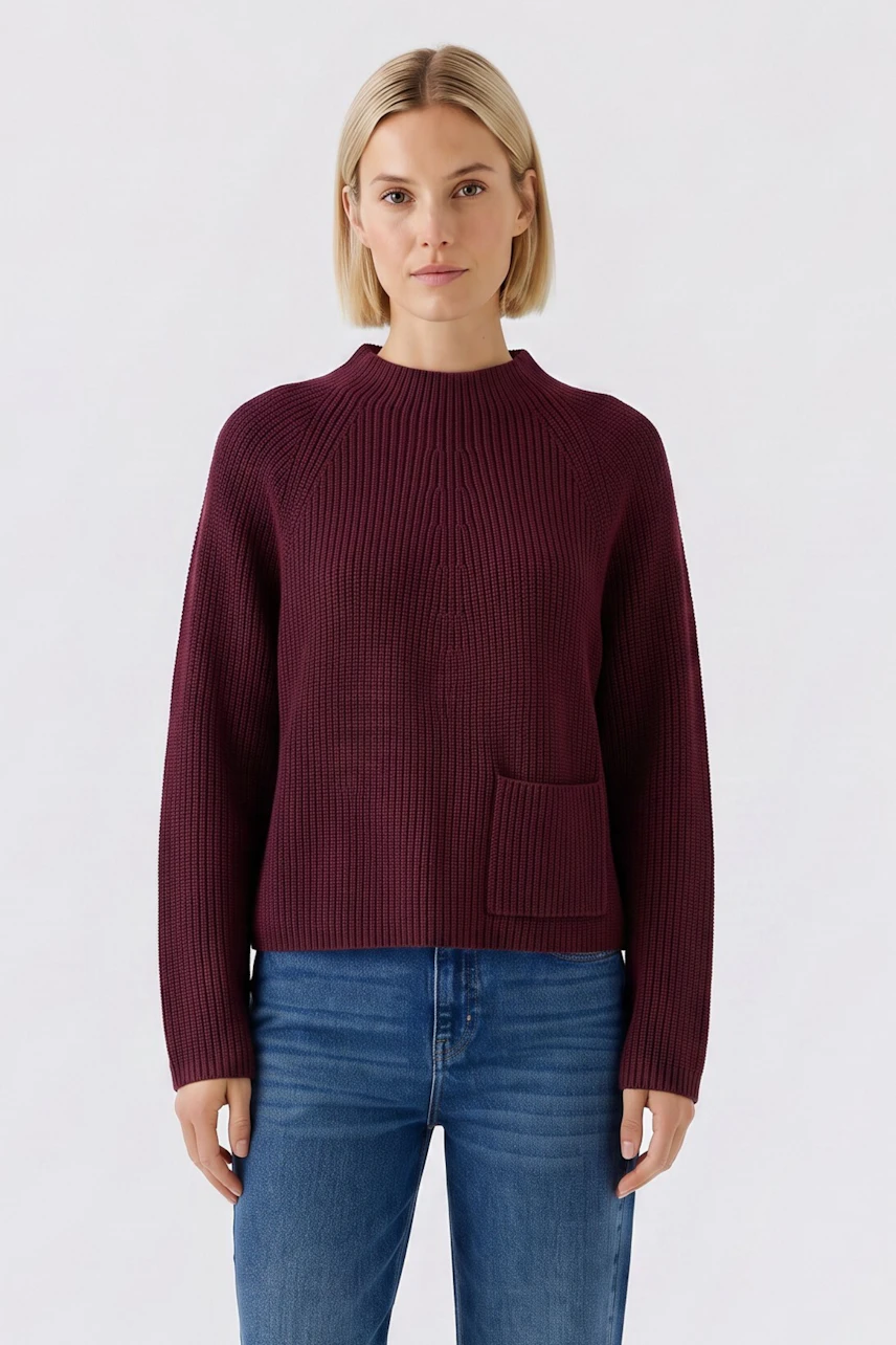 Casual women's pullover: Woman in a burgundy knit pullover with a front pocket, paired with blue jeans.