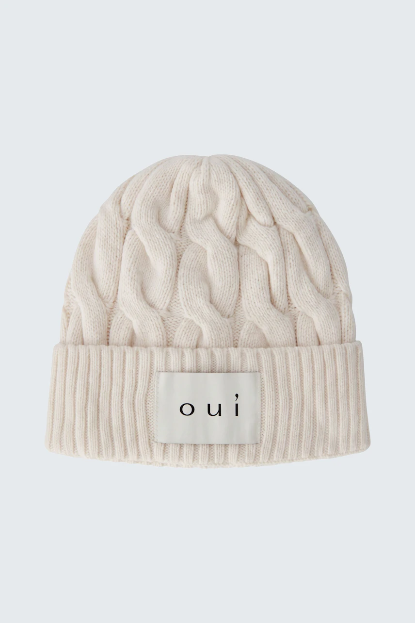 Cozy knit hat: Cream cable-knit beanie with "oui" logo, perfect for chilly days.