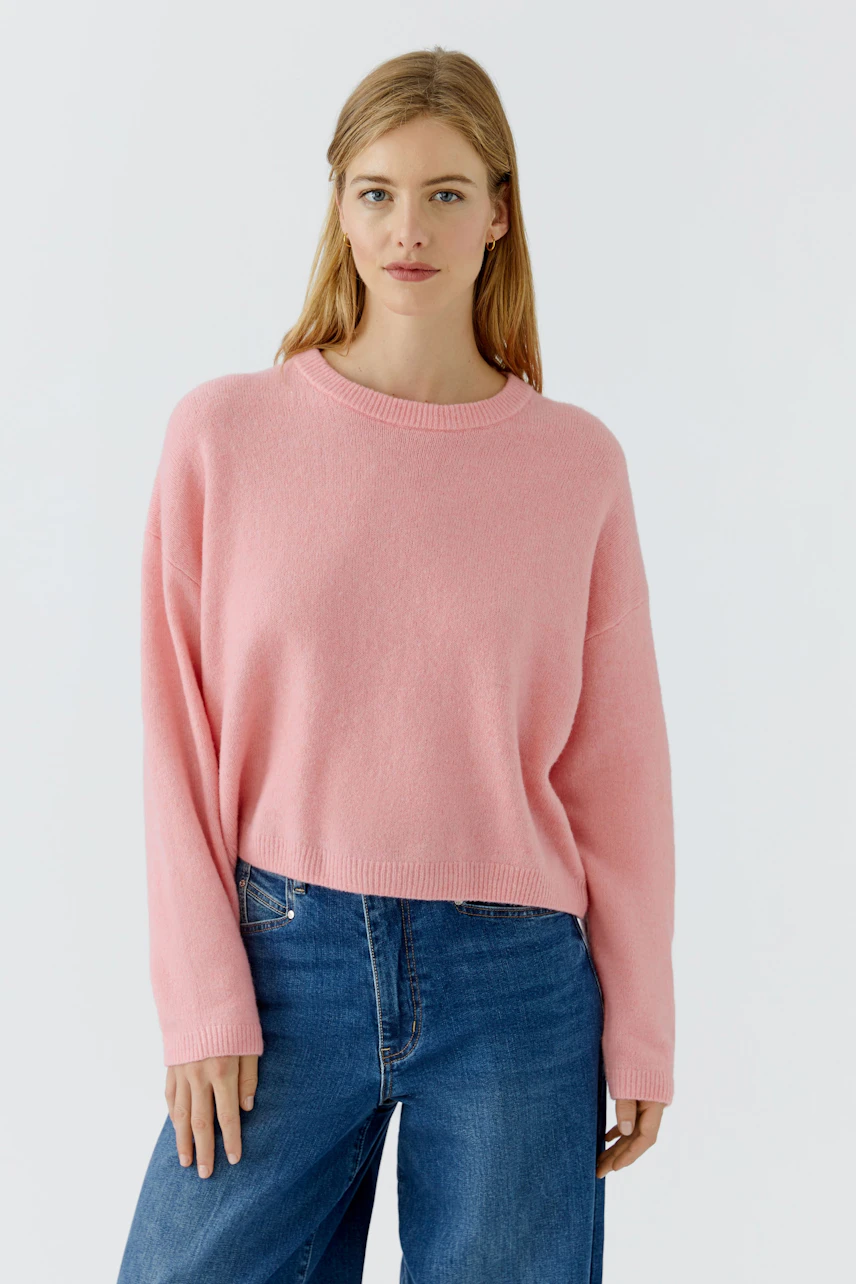 Lässiger Damen-Pullover: Frau im rosa Pullover und blauen Jeans, schlicht und modern.