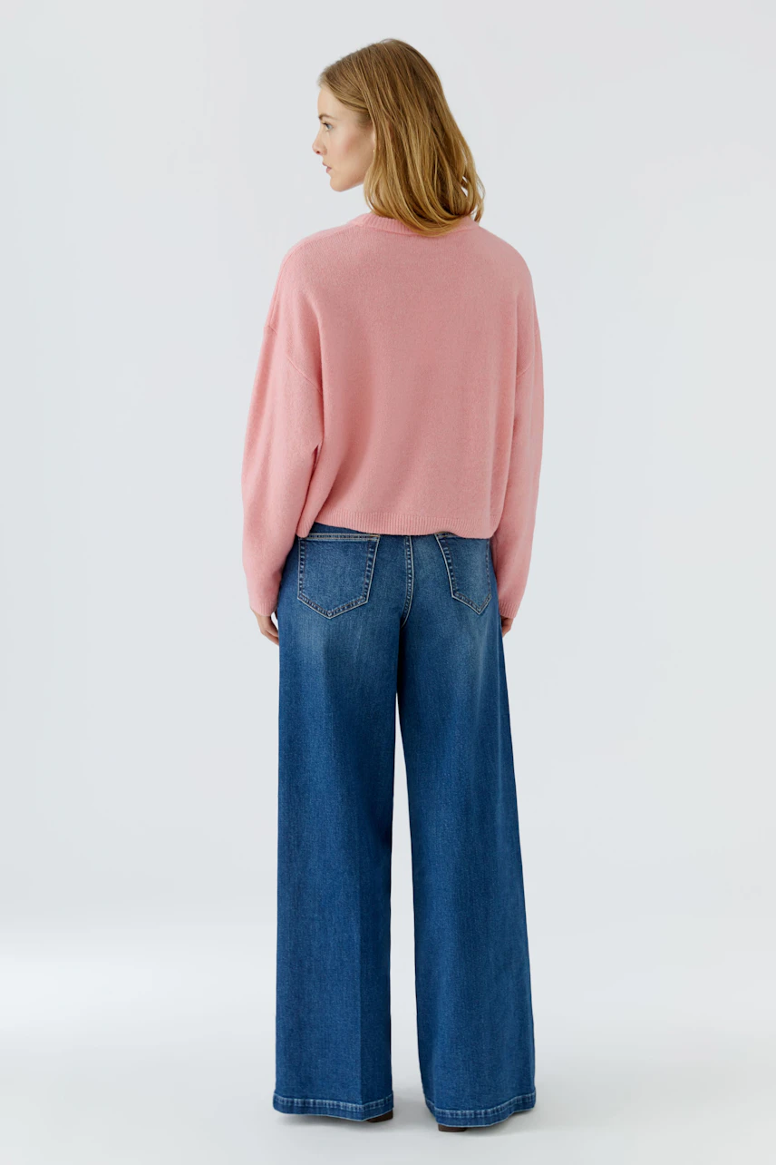 Lässiger Damen-Pullover: Frau im rosa Pullover und blauer Jeans von hinten, entspanntes Design.