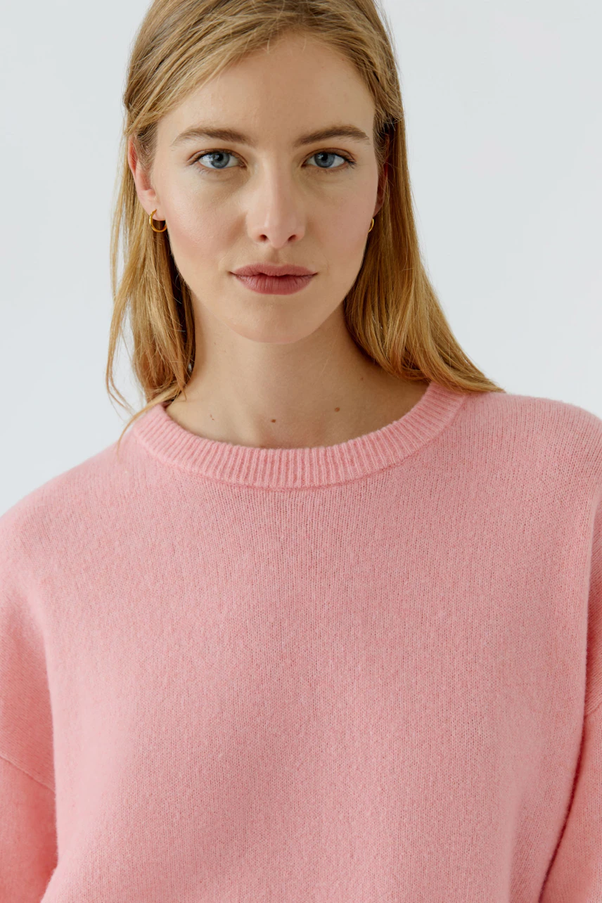 Frau im rosa Pullover: Schlichter, weicher Pullover, ideal für einen lässigen Look.