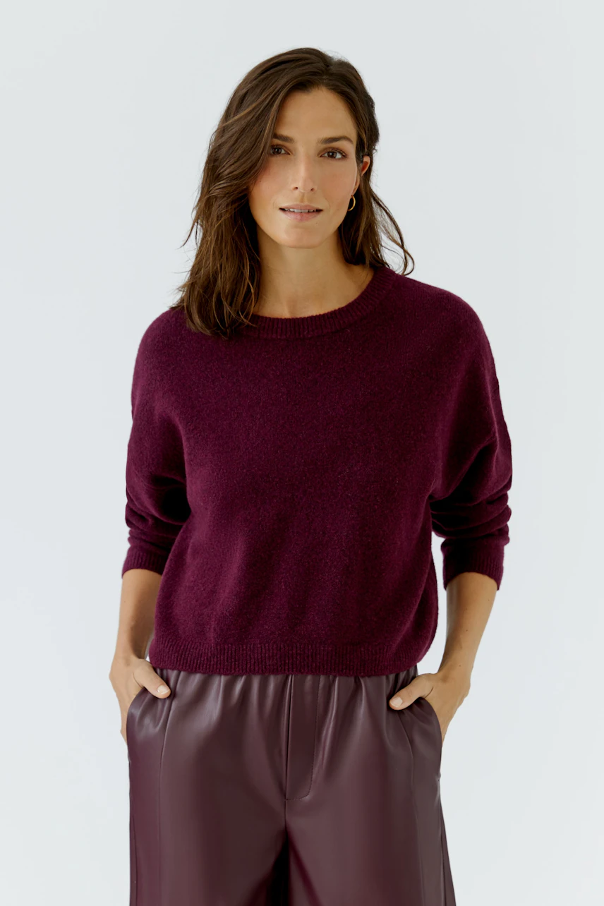 Frau im weinroten Pullover, kombiniert mit passender Hose, lässig und modern.