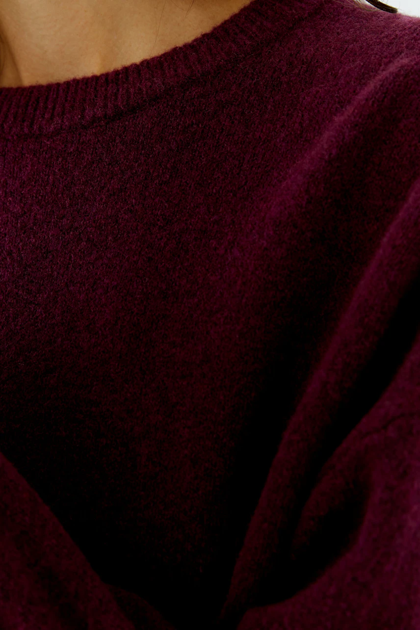 Damen-Pullover: Frau in weinrotem Pullover mit weichem Stoff und Rundhalsausschnitt.