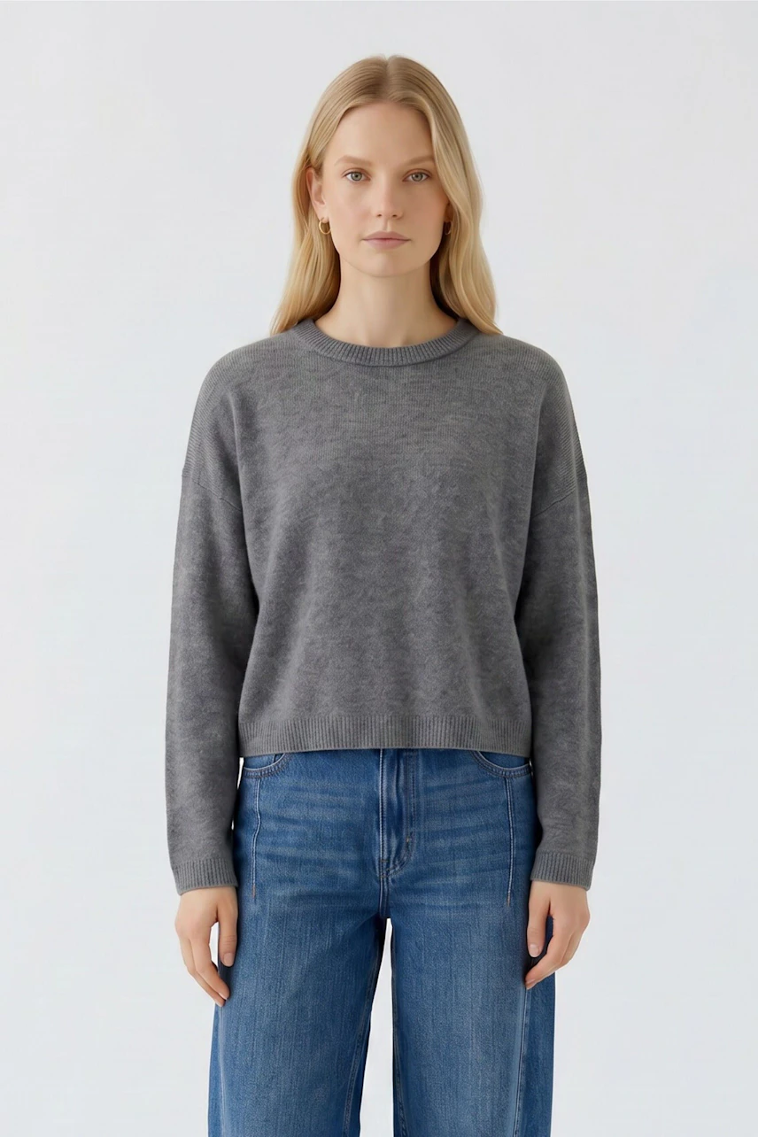 Lässiger Damen-Pullover: Frau im grauen Pullover und blauen Jeans, schlicht und modern.