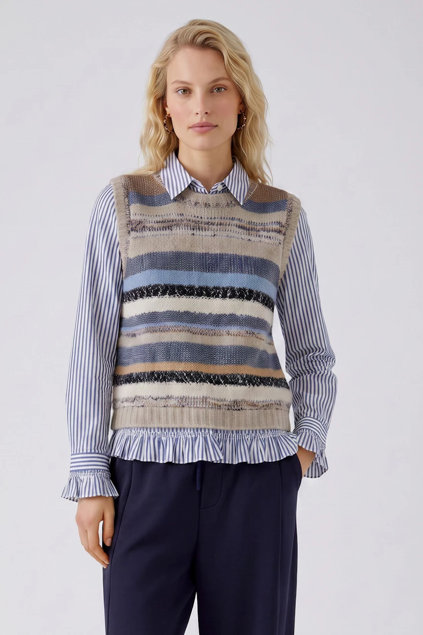 Casual women's pullover: Woman in a striped sleeveless pullover with blue and beige tones, looking relaxed.