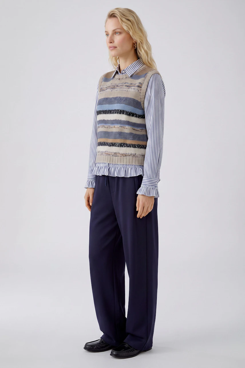Casual women's pullover: Woman in a striped sleeveless pullover with blue, beige, and black tones.