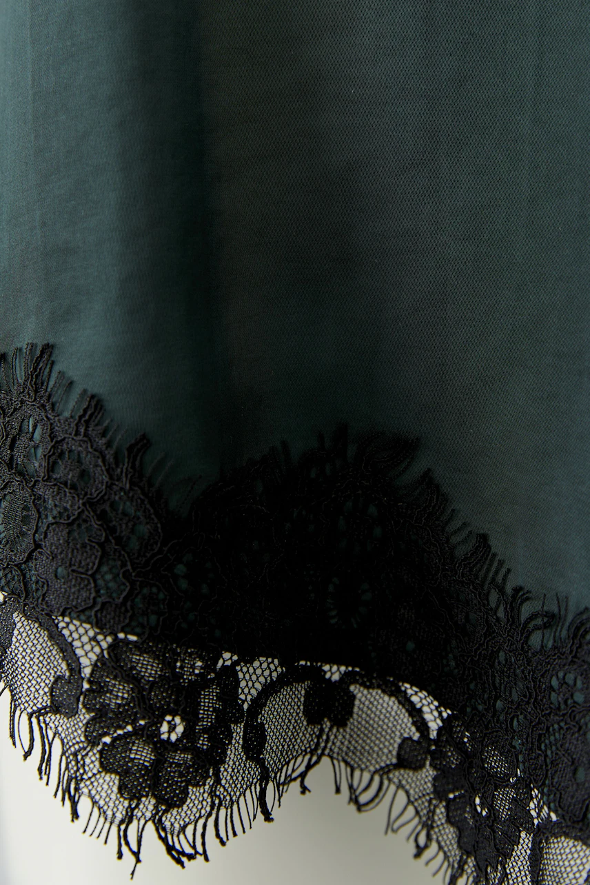 Women's top with black lace hem, showcasing intricate floral patterns on a dark fabric.