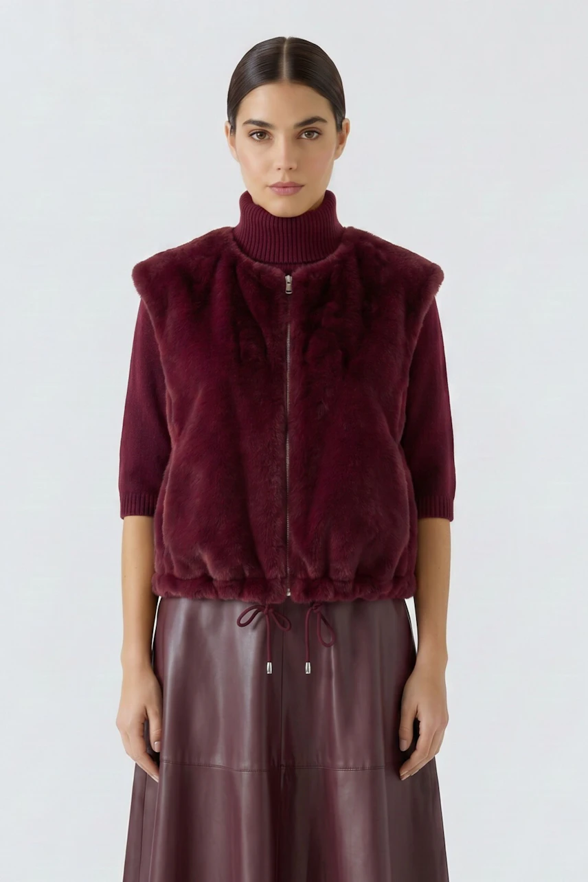 Woman in a burgundy vest with a high-neck sweater and matching skirt, looking confidently ahead.