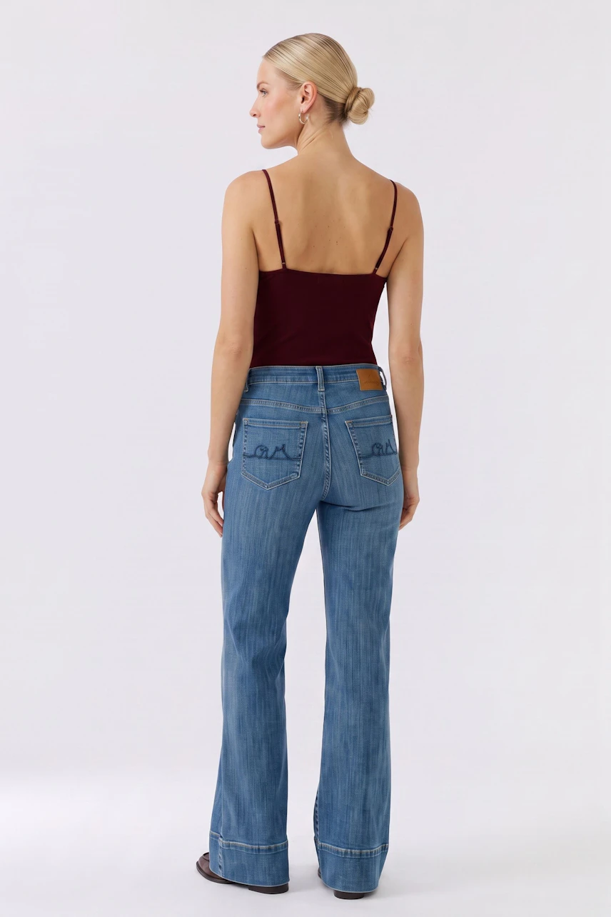 Woman in flared jeans and burgundy top, showcasing casual style from the back.