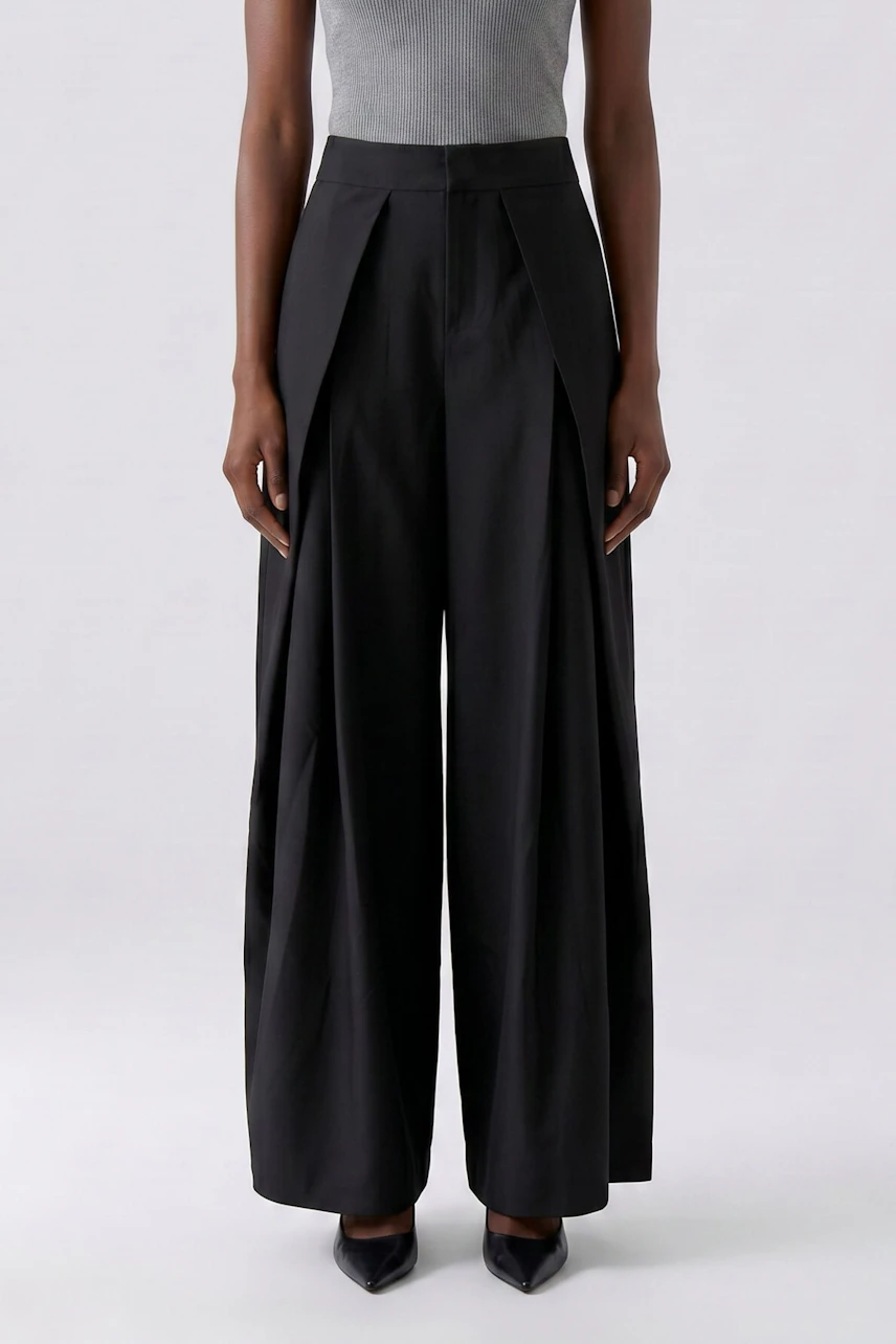 Woman in black pleated trousers, gray top, and black heels. Focus on the wide-leg design of the trousers.