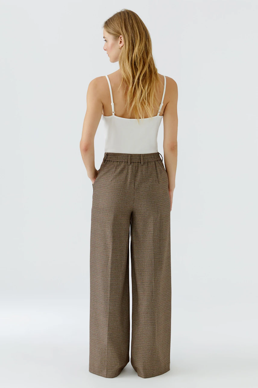 Casual women's pants: Woman in wide-leg brown pants and white top, viewed from the back.