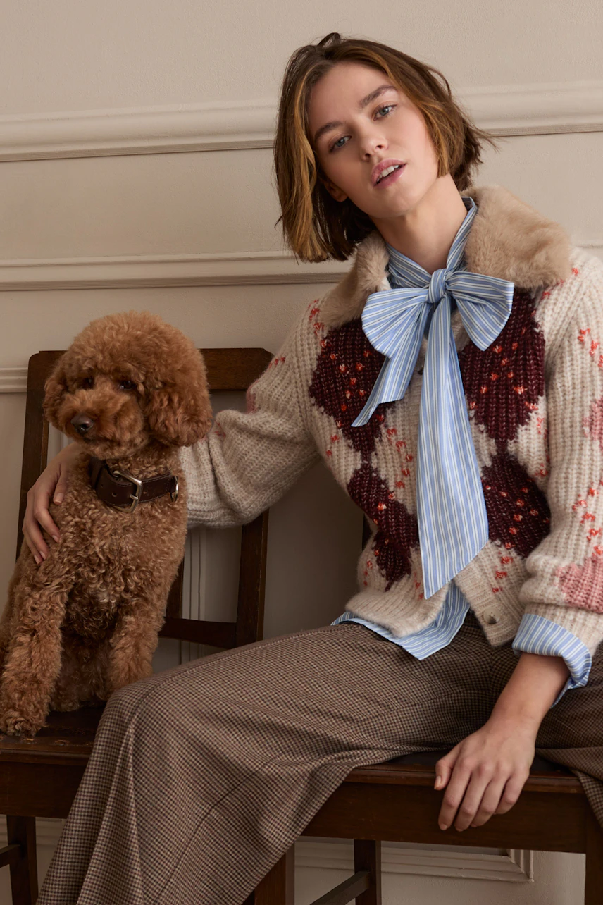 Casual trousers: Woman in checkered trousers with a cozy cardigan and a dog, sitting relaxed.