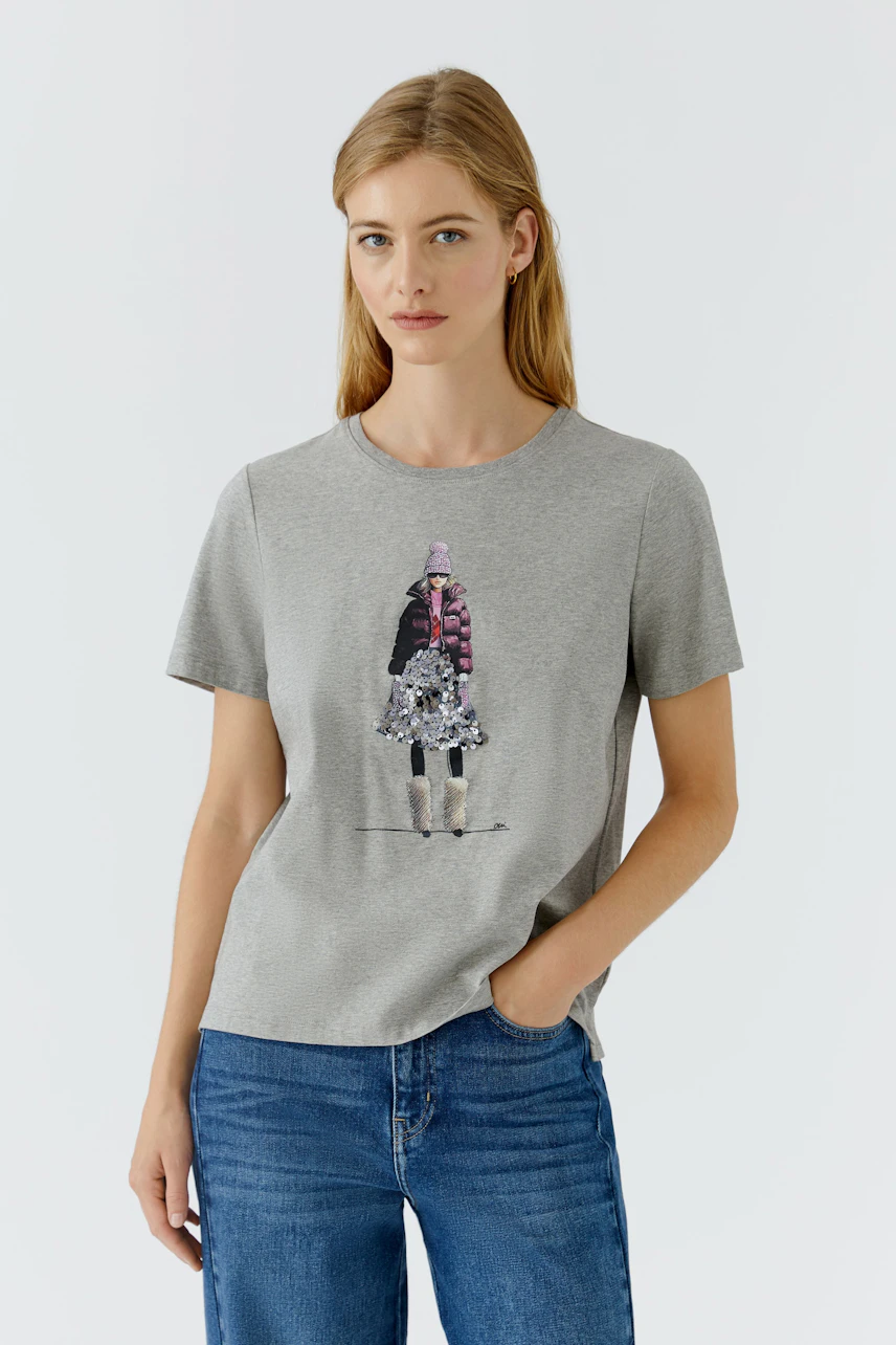 Casual women's T-shirt: Woman in a gray T-shirt with a graphic print, paired with blue jeans.