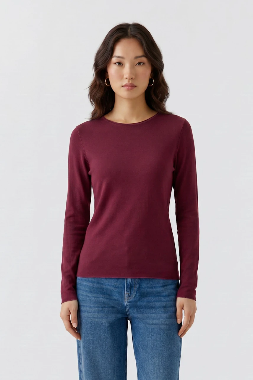 Frau im weinroten Langarmshirt und Jeans. Schlichtes Design, ideal für den Alltag.