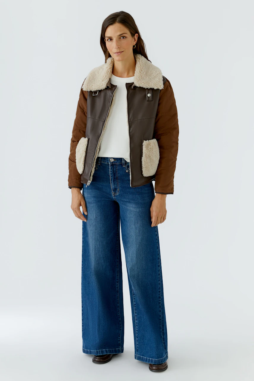 Casual outdoor jacket: Woman in brown jacket with shearling collar, white top, and wide-leg jeans.